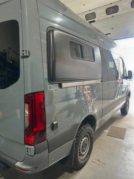 Grey custom Sprinter camper van, ready for rv rental. Features side pop-out and all-terrain tires for adventure.. Mercedes Sprinter 2022
