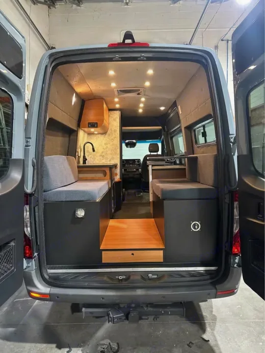 Explore this converted camper van's interior. Designed for RV rental, it features comfy benches, a kitchen, and a clever step with storage.. Mercedes Sprinter 2022
