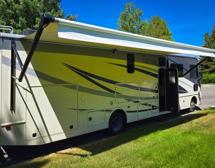Side view of a Flair RV rental, parked with its LED-lit awning extended & door open on a sunny day.. Flair-Fleetwood Flair-Fleetwood Motorhome 2019