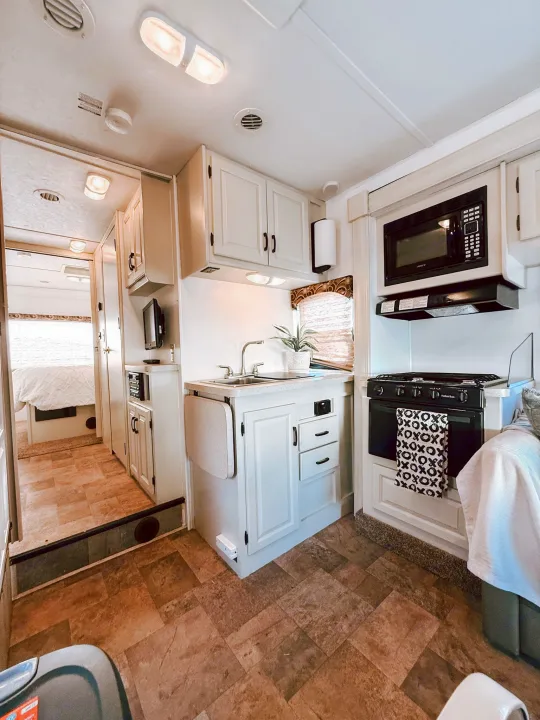 Explore this clean RV rental interior! A functional kitchen, cozy living area, and bedroom beyond for your road trip comfort.. Forest River Sunseeker 2015