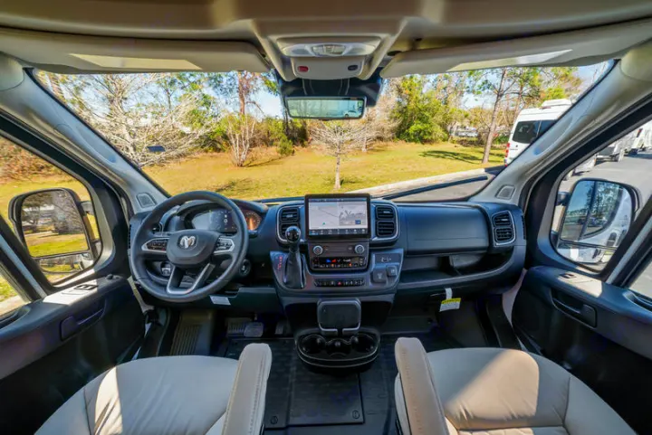 RV rental interior: driver's cockpit with modern dash, large touchscreen, steering wheel, and comfortable seating.. Coachmen PIXEL 2026