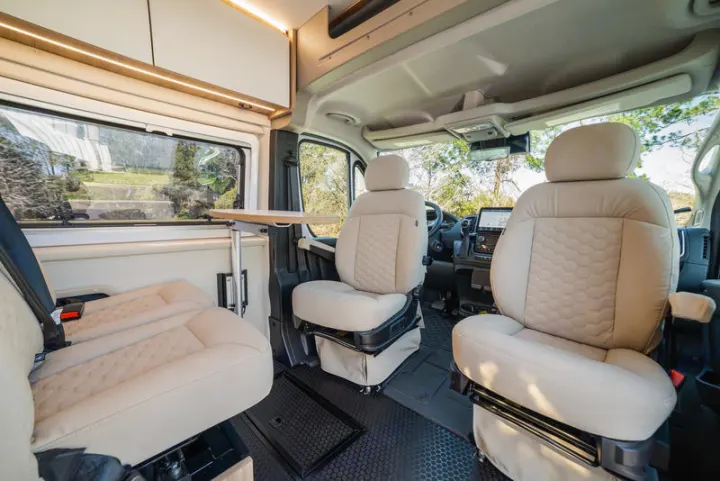 Spacious and modern RV rental interior featuring swiveling front seats, a foldable table, and a comfortable rear bench seat.. Coachmen PIXEL 2026