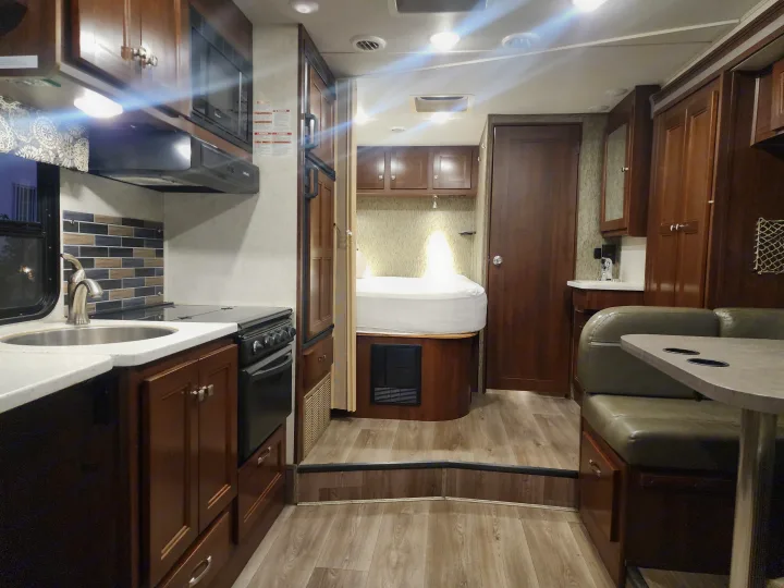 Functional RV rental interior featuring a bright kitchen, a raised bed area, and a practical dining booth.. Forest River Forester 2018
