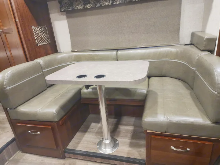 Cozy RV rental dinette features U-shaped booth seating, table with cupholders, and integrated storage. Ideal for travel.. Forest River Forester 2018