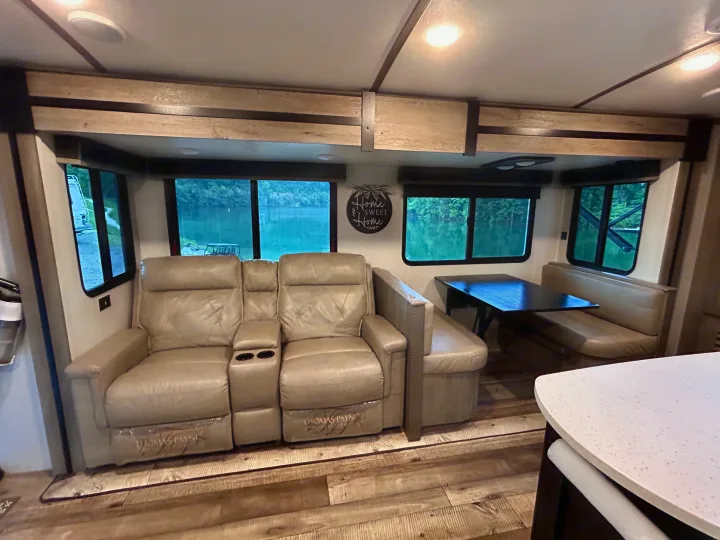 RV rental interior: light-colored recliners, dinette, and expansive lake views from wide windows create a serene living space.. Keystone RV Outback 2021