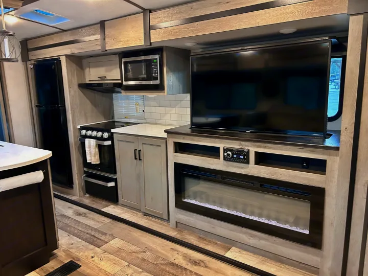 RV rental's modern kitchen & entertainment area, featuring fridge, stove, microwave, TV, stereo, and fireplace.. Keystone RV Outback 2021