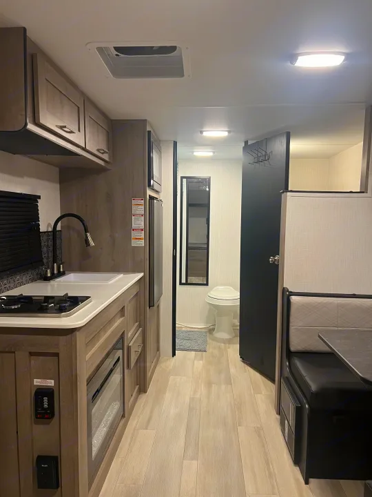 Spacious RV rental interior featuring a modern kitchenette, compact dining, and bathroom, ideal for comfortable travel.. Heartland Prowler Lynx 17BHX 2025
