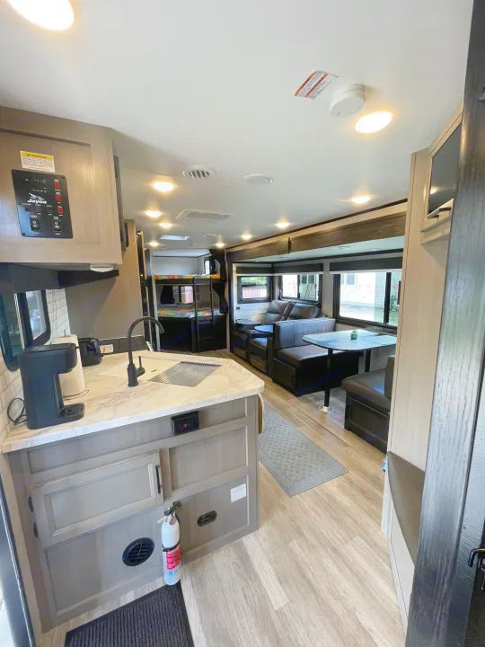 Spacious RV rental interior showcasing a bright kitchen, living area with recliners & dinette, and cozy bunk beds in the rear.. Jayco Jay Feather 2022