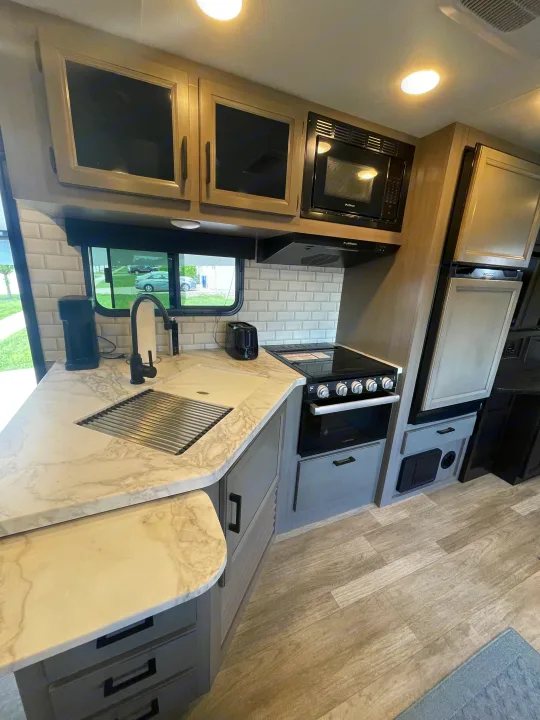 RV rental: Modern kitchen with marble counters, sink, stove, microwave, fridge, & white subway tile. Bright and functional.. Jayco Jay Feather 2022