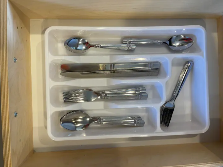 Neatly organized silverware – spoons, knives, forks – in a white tray inside a light wood RV rental kitchen drawer.. Jayco Jay Feather 2022