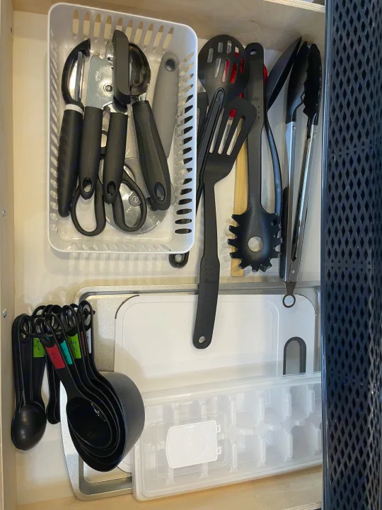 Organized kitchen drawer in an RV rental, featuring cooking utensils, measuring cups/spoons, and a cutting board.. Jayco Jay Feather 2022