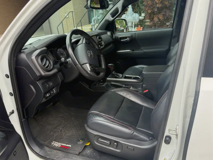 Driver's view of a clean, modern truck's black interior with leather seats, dashboard, and steering wheel. A comfortable alternative to an rv rental.. Toyota Tacoma TRD-Pro 2020
