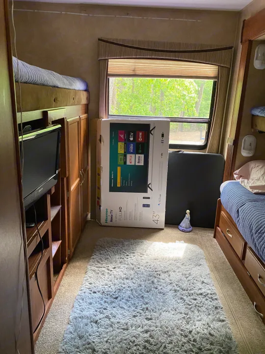 Inside an RV rental, a new 43" Roku TV box stands ready for setup, highlighting a cozy living space with bunk beds.. Jayco Eagle Super Lite 2010