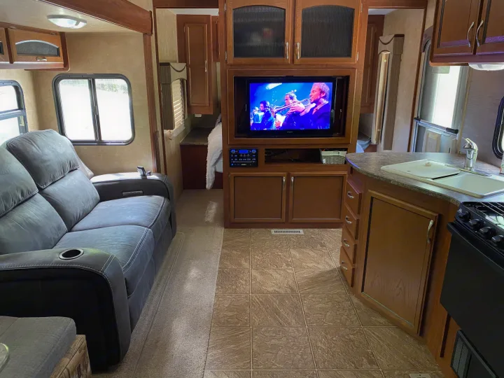 Cozy RV rental interior featuring a comfy sofa, entertainment center, and fully equipped kitchen. Perfect for your next adventure!. Jayco Eagle Super Lite 2010