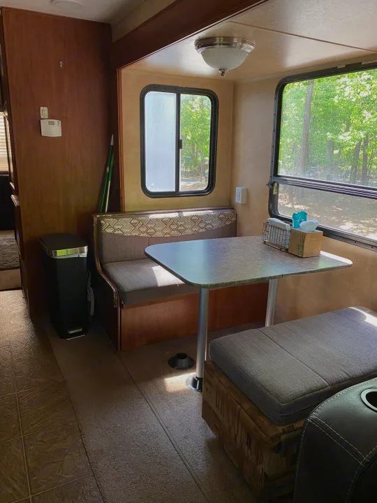 Inside an RV rental: a compact dinette with bench seating, table, and bright windows looking outside.. Jayco Eagle Super Lite 2010