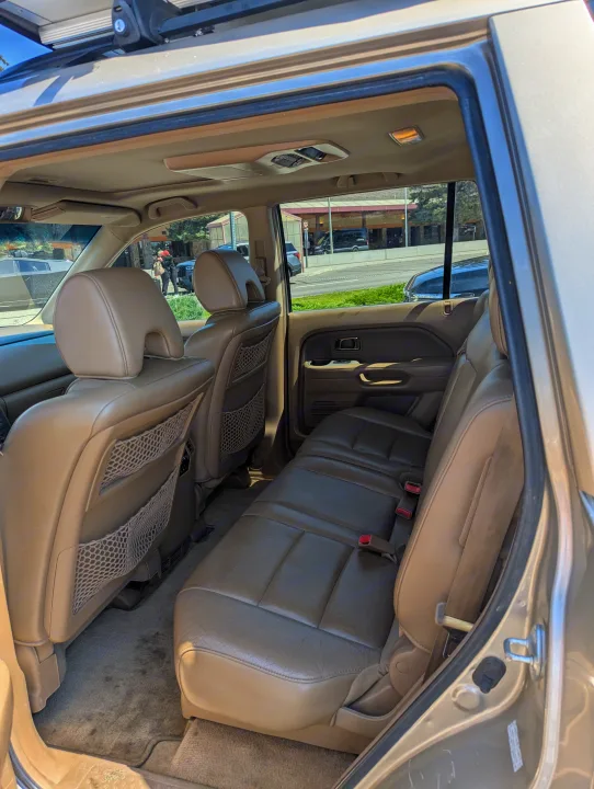 Spacious SUV interior with tan leather seats, seen from the rear passenger area. An ideal rv rental option for family travel.. Honda Pilot 2007