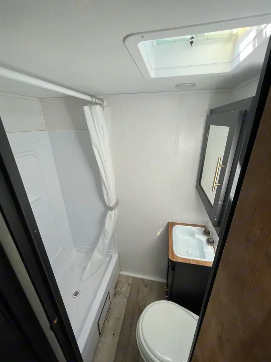 Compact RV rental bathroom featuring a shower, toilet, and sink, designed for efficient use of space.. Keystone RV Springdale 2022