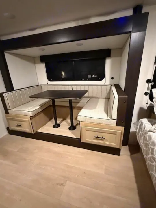 Spacious RV rental dinette: U-shaped seating, light cushions, dark table, & drawer storage.. Forest River Cherokee Wolf Pup 2026