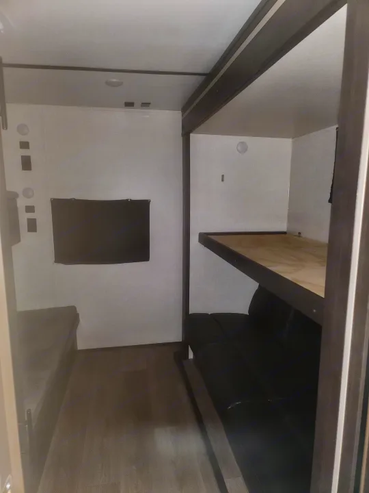 RV rental interior showing a bunk bed over a sofa and a bed on the left, optimizing compact space.. Crossroads RV Cruiser Aire 2021