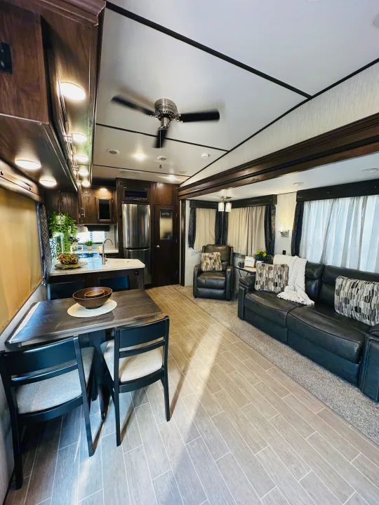 Modern RV rental interior with full kitchen, dining table, and cozy living room. Bright & spacious for your next adventure.. Forest River Cherokee Arctic Wolf 2019