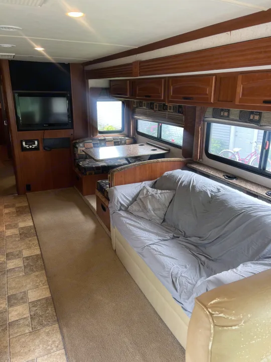 Spacious RV rental interior with dinette, couch, TV, and wood cabinetry, offering comfortable living space.. Fleetwood Fiesta LX 2010