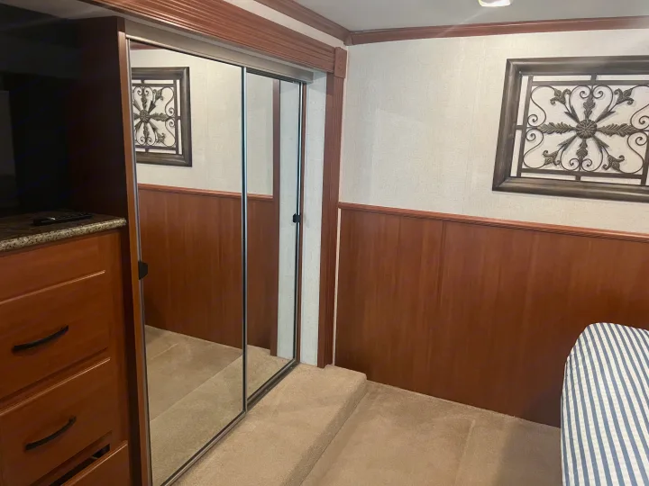 Cozy RV rental bedroom with mirrored closet, dresser, and patterned bedding, offering functional space.. Fleetwood Fiesta LX 2010