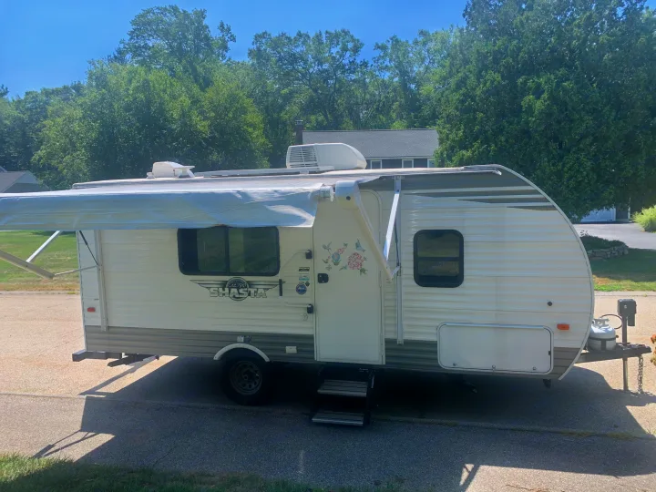 White Shasta travel trailer with awning extended, a spacious option for rv rental adventures.. Forest River Shasta 2021