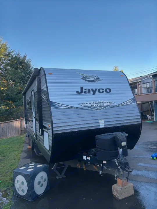 A large, grey Jayco Rocky Mountain Edition RV travel trailer is parked in a driveway, ready for an RV rental adventure.. Jayco Jay Flight SLX Rocky Mountain Edition 2020