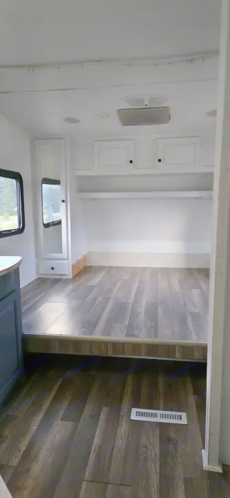 Bright RV rental interior showcasing new wood-look flooring, white cabinets, and a comfortable sleeping area.. R-Vision Trail-Lite Trail-Bay 2005