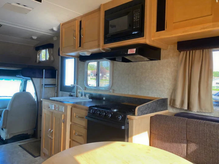 Spacious RV rental interior with full kitchen (microwave, stove, sink), dining area, and cab-over bed.. Adventurer Adventurer Motorhome 2008