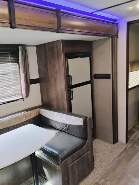 This RV rental features a dinette with patterned bench seating, a table, a built-in refrigerator, and purple LED accent lighting.. Crossroads RV Volante 2019