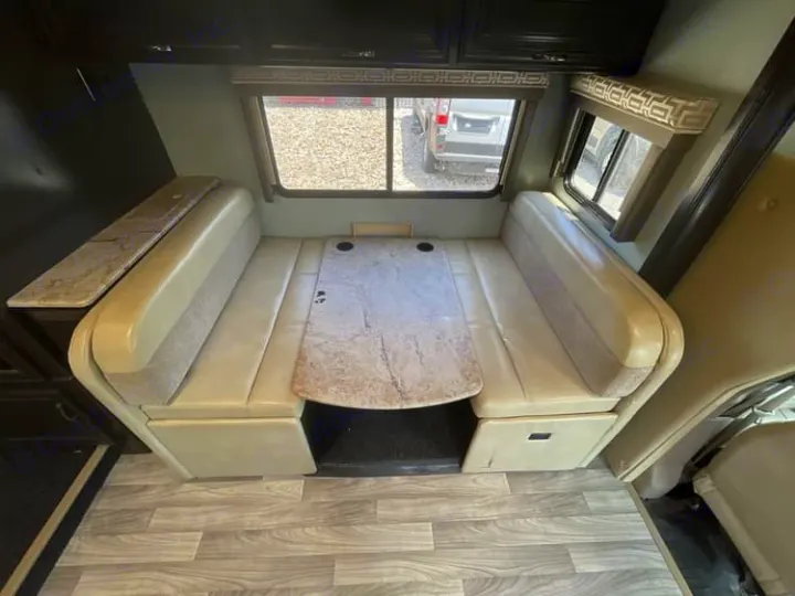 Inside an RV rental: a spacious dinette with cushioned benches, a table, and practical counter space.. Thor Quantum 2018