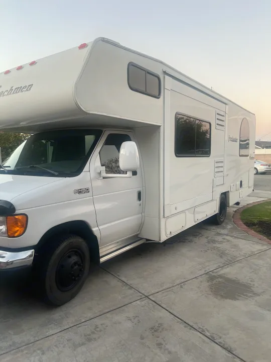 White Coachmen Freelander Class C RV rental on Ford E450 chassis, parked on a concrete driveway.. Coachmen Freelander 2007