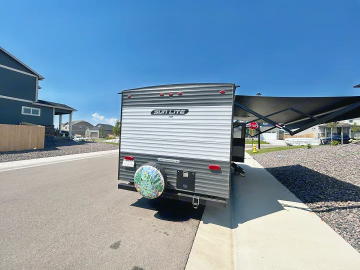 A Sun Lite LTD travel trailer, ideal for an rv rental, parked on a residential street with its awning out under a clear sky.. Sunset Park & Rv Inc. 21bt 2026