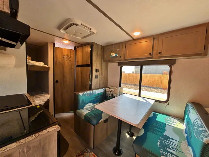 Cozy RV rental interior with a dinette, kitchen area, and bunk beds. Ready for your next adventure.. Sunset Park & Rv Inc. 21bt 2026
