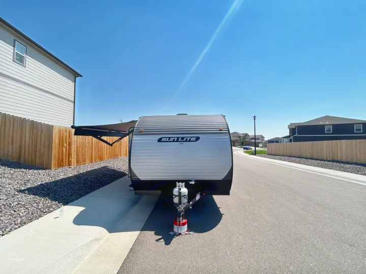 RV rental: Sun Lite travel trailer parked on a sunny residential street with awning extended, ready for adventure.. Sunset Park & Rv Inc. 21bt 2026