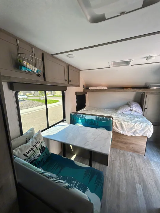 Spacious rv rental interior with a cozy dinette, nature-themed cushions, comfortable beds, and overhead storage for your travels.. Sunset Park & Rv Inc. 21bt 2026