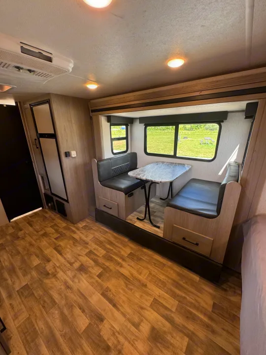 RV rental interior: cozy dinette with scenic views, wood floors, and functional refrigerator. Ready for adventure!. Dutchmen Kodiak Cub 2022