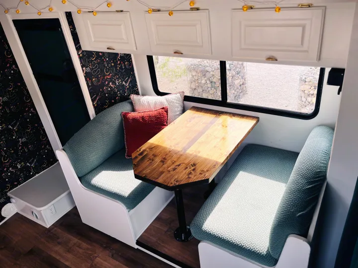 Stylish RV rental interior with a cozy dinette, custom wooden table, and whimsical dark wallpaper. Ready for adventure!. Coachmen Freelander Premier 2006