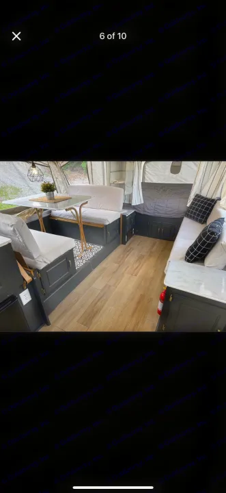 Experience this cozy RV rental's modern interior: dining area, sleek dark cabinetry, and comfortable bed.. Coleman Grand Tour 2002
