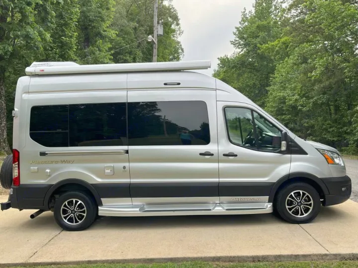 Silver Pleasure-Way Ontour 2.0 camper van, perfect for an RV rental, parked on a paved lot with trees in the background.. Pleasure-Way Pleasure-Way Class B 2023