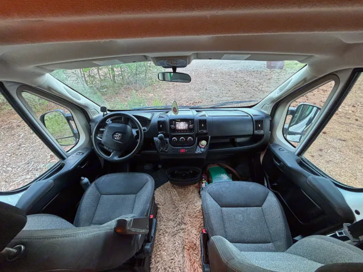 RV rental: Interior view of a van's front cabin, featuring the steering wheel, dashboard, and comfortable seats looking outside.. RAM Promaster 2500 2018