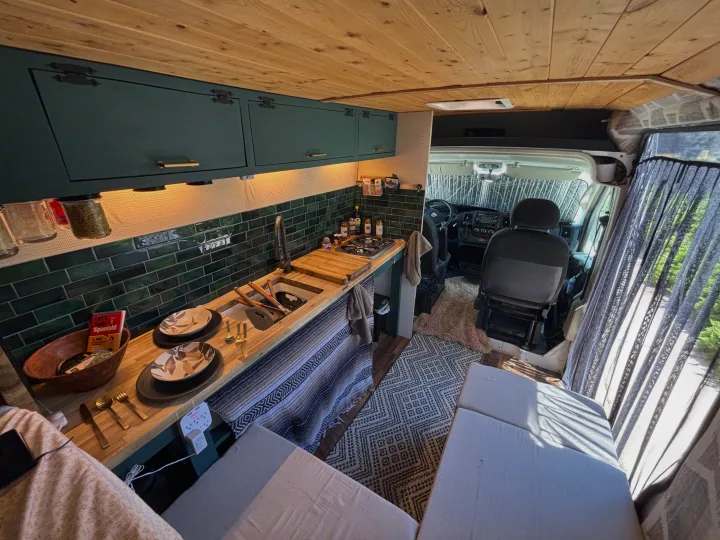 Custom rv rental camper van interior: a cozy kitchen, wood ceiling, and seating area for travel adventures.. RAM Promaster 2500 2018