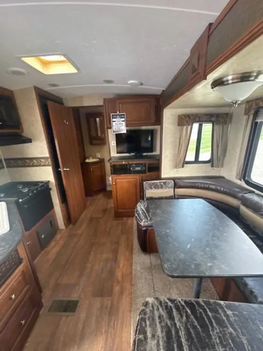 Spacious RV rental interior featuring a kitchen, U-shaped dinette, and entertainment center setup.. Keystone RV Bullet Ultra Lite 2014