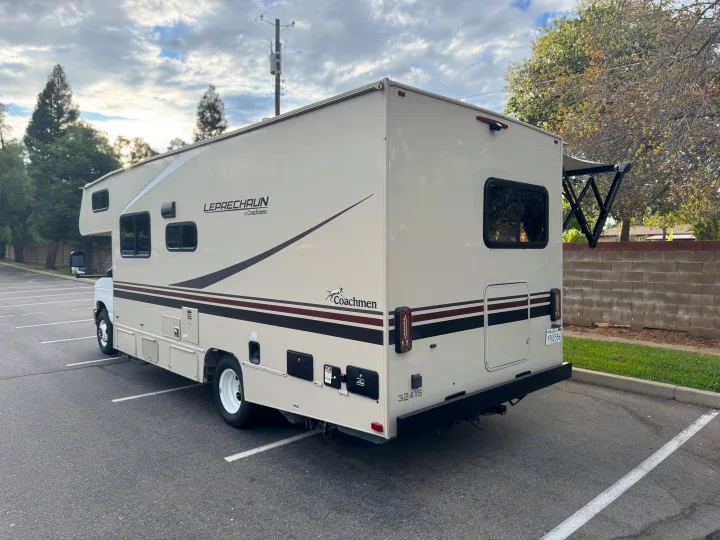 A spacious Class C Coachmen Leprechaun RV rental, light-colored and parked outside, ideal for travel.. Coachmen Leprechaun 23CB 2022