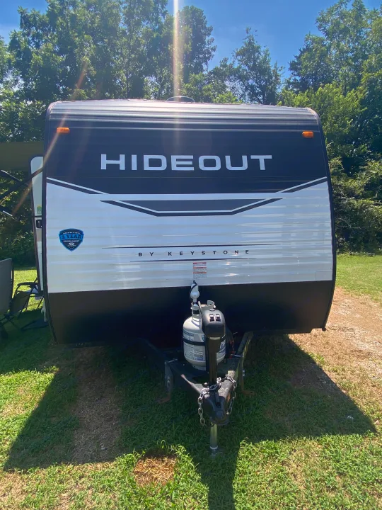 This Hideout by Keystone travel trailer is ready for your next RV rental adventure, parked on green grass under a sunny sky.. Keystone RV Hideout 2022
