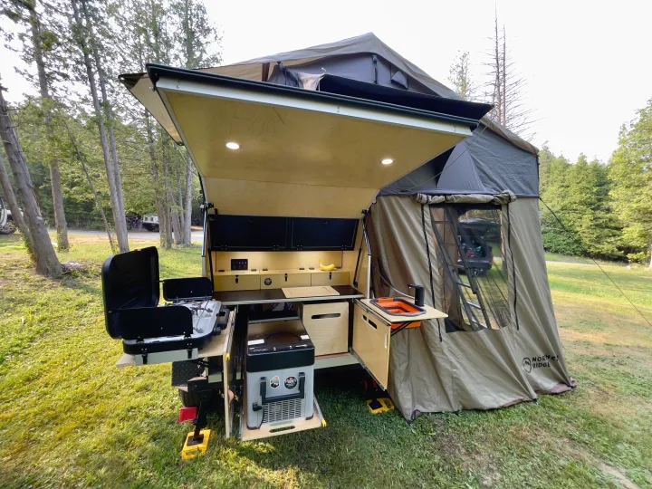 An RV rental overland trailer with a fully equipped outdoor kitchen and tent annex, ready for camping adventures.. Nutshell Campers Nutshell Camper 2025