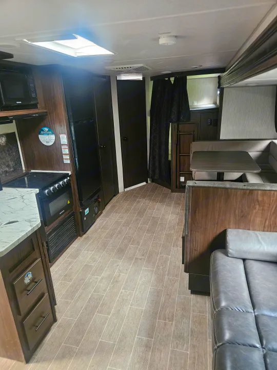 Explore this modern RV rental interior! Features a well-equipped kitchen, comfy dinette, and stylish living area with a sofa.. Forest River Cherokee Grey Wolf 2021