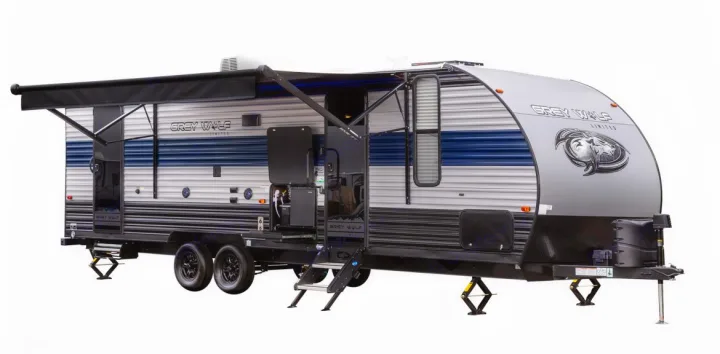 Modern silver & blue Grey Wolf travel trailer RV for rental, with open awning, steps, and stabilizers deployed.. Grey Wolf 26DBH 2025