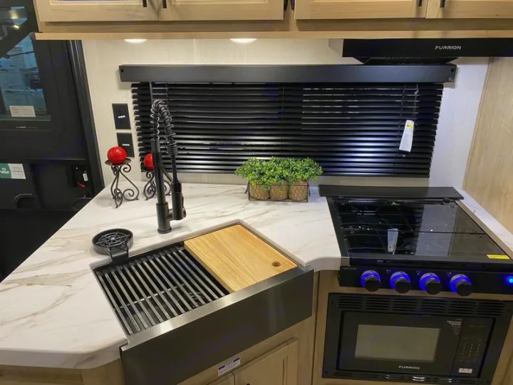 Step inside a modern RV rental. This kitchen boasts a large sink with a cutting board, a stove, and a microwave.. Grey Wolf 26DBH 2025